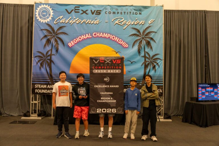 Team 24580A Inferno standing in front of the VEX California Region 4 Regional Championship banner, holding their Excellence Award trophy